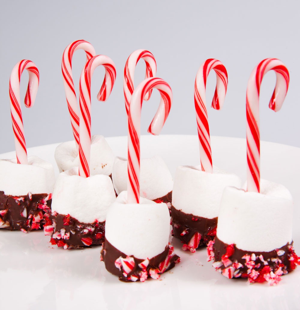 Este es un detalle para el deleite de los más pequeños. Bañe malvaviscos con chocolate y decore con caramelo. Inserte en cada uno un bastón de Navidad.