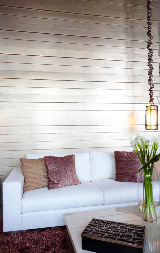Una pared de tablones de madera combina con un sofá en crudo.
