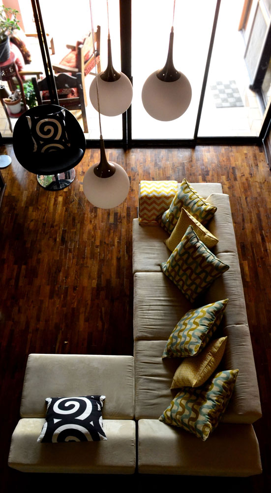 El modelo del sofá es de líneas rectas con una base alta de madera. Tela de microfibra, y almohadones de varios colores como acento