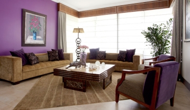 La mesa central de la sala es con enchape de madera, hierro y mármol. Los sofás neutros tienen como acento los almohadones en tonos uva, negro y dorado. Cenefa de madera y cuadro de Latasse.