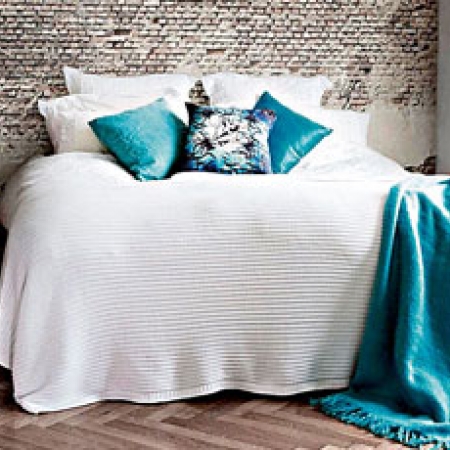 La pared de fondo de este dormitorio principal aparenta ser de piedra gastada, todo un efecto logrado con papel. Nótese la combinación de grises, blanco antiguo y celestes.